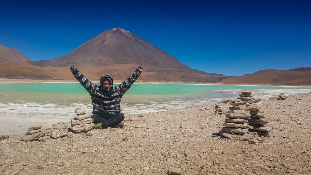A man is sitting on the beach with his arms raised in the air